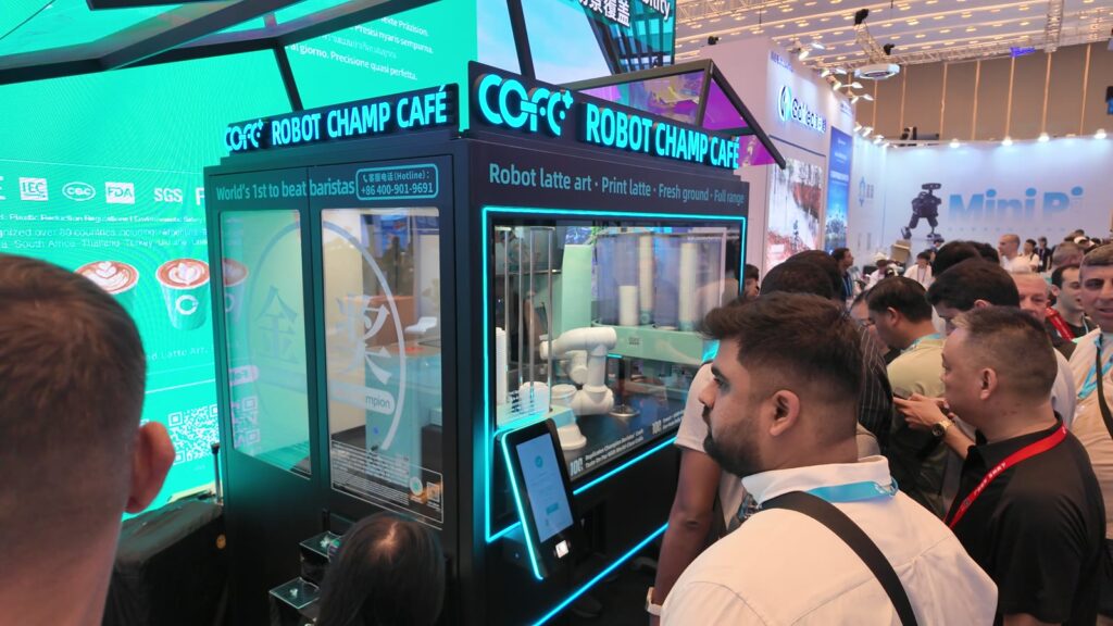 COFE+のロボットカフェ。ガラス越しにアームの動きを見る来場者